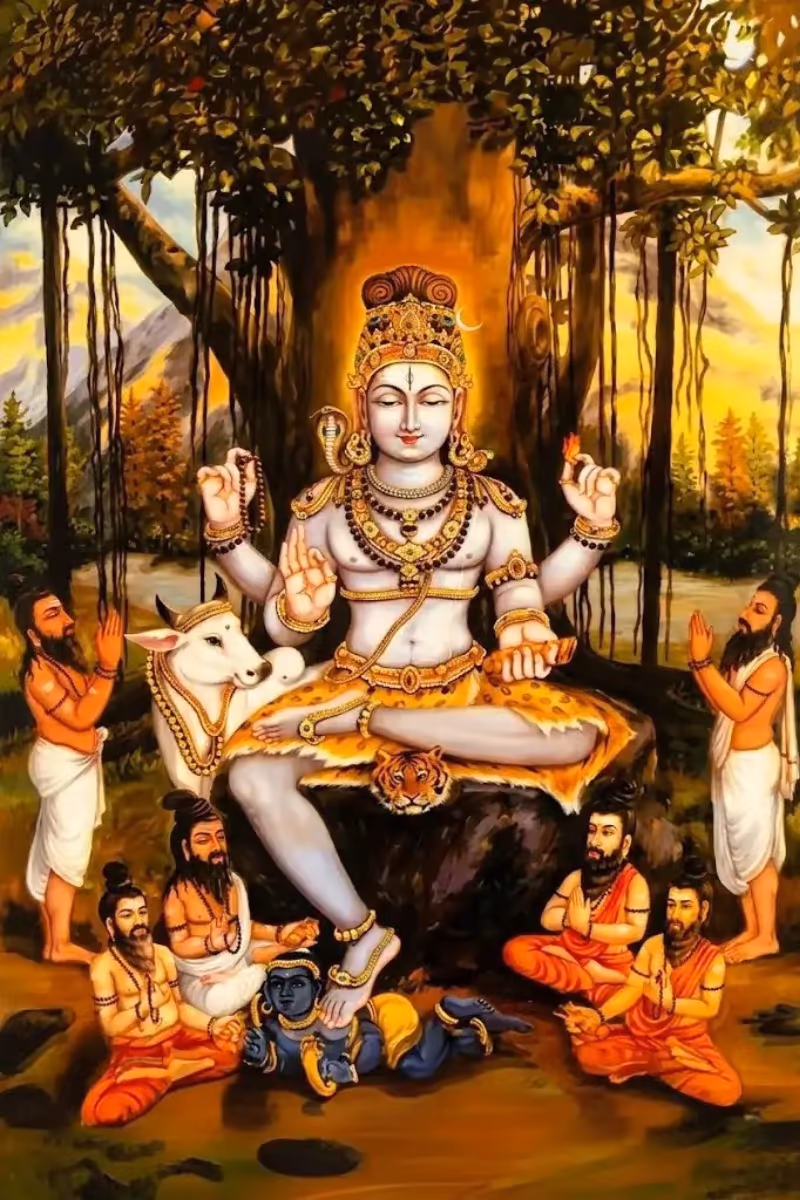 A vibrant, traditional Hindu painting of Lord Shiva in His Dakshinamurthy form, seated under a large banyan tree. He has four arms, holding a mala (rosary) and a flame, with His primary right hand forming the Chinmudra (gesture of knowledge). He sits on a tiger skin, with His right foot resting on the demon Apasmara, symbolizing the conquering of ignorance. Seven bearded sages sit reverently at His feet with folded hands, and a white cow stands peacefully in the lush forest background.