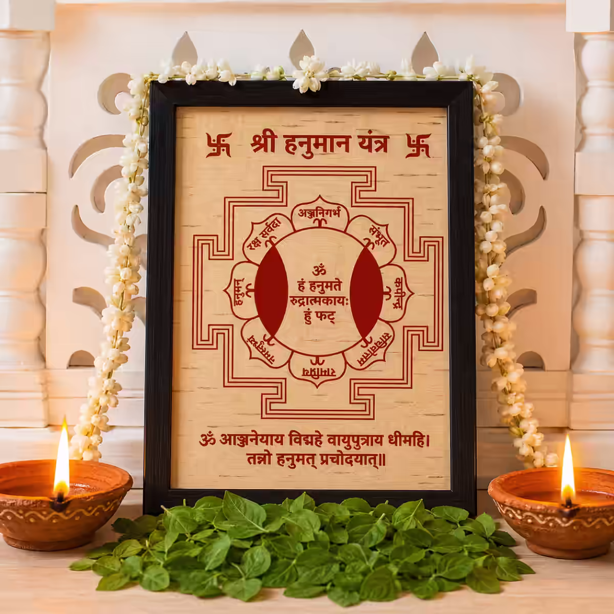 Framed Sri Hanuman Yantra on Bhojpatra with tulsi leaves, mogra garland, and ghee diyas for a guided Sri Hanuman sadhana purashcharana kit with rules and restrictions.